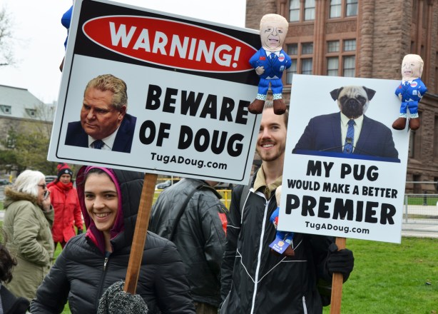 Warning! Beware of Doug says a sign, with picture of Doug Ford on it. Another sign says My pug would make a better premier 