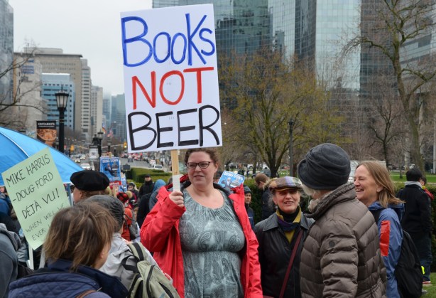 a woman holds a sign that says books not beer