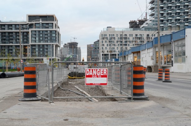 danger sign on construction zone in the middle of the street, Queens Quay, looking west along the street towards downtown toronto 