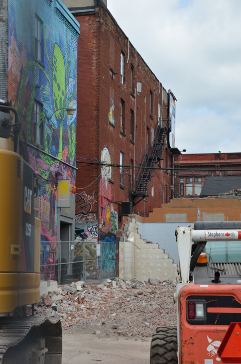 demolition of building in graffiti alley, remaining buildings in the background