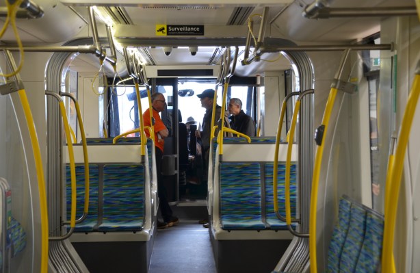 a few people talking at the front of new Crosstown train, from farther back in the train.