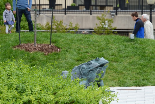 two bronze sculptures of frogs in a park 