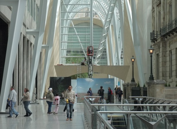 people in Allan Lambert Galleria, a couple of large photos, a workman on a crane, 