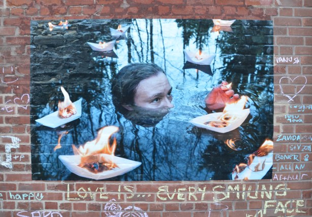 a head partially submerged in water, surrounded by little white trays with flames