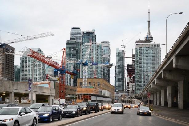 downtown Toronto, looking west towards all the tall buildings, looking along the Lakeshore with lots of traffic on it, many buildings in the foreground under construction with 7 cranes in the photo