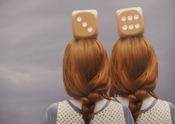 close up of a Patty Maher photograph, Parallel Universe, the back of two red headed women, both with large dice on their head, one die per head,