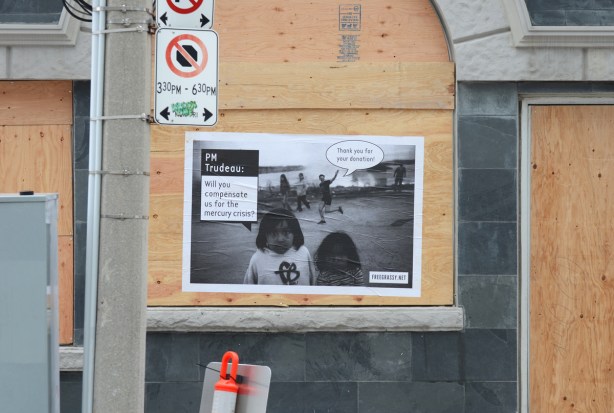 large black and white poster on an empty building with plywood covering doors and windows. 