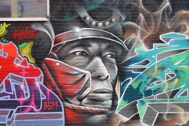 black and white painting of a man's face, very large, part of a mural in an alley