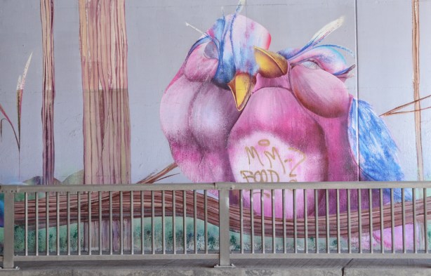 part of a mural by Christopher Ross on an underpass wall in pinks and blues, a pink bird