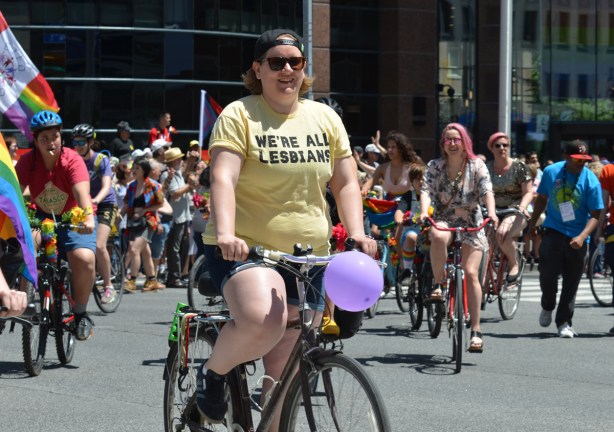 dykes on bikes at start of parade, one is wearing a yellow t shirt that says We're all lesbians