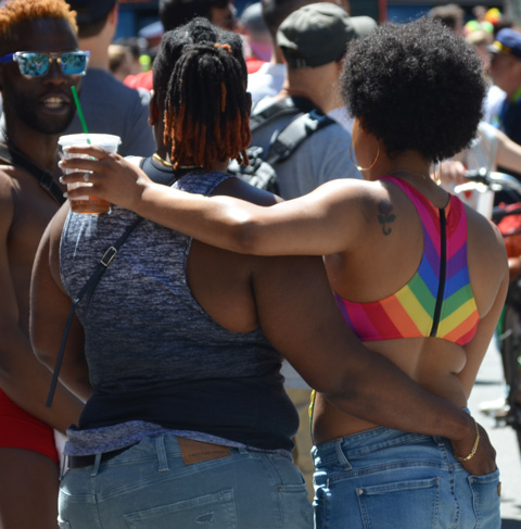 two black women, arm in arm, from the back