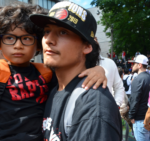 Raptors championship parade day, , a father carries his son, a boy with curlyhair and black glasses 