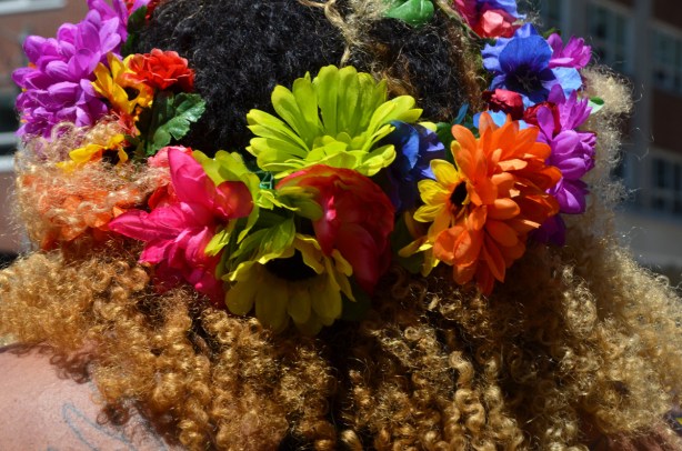 colourful flowers in curly black and brown hair on someone's head, from the back, close up shot