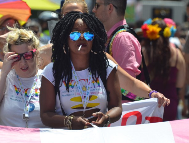 a black woman in dreadlocks, blue sunglasses and smoking a cigarette