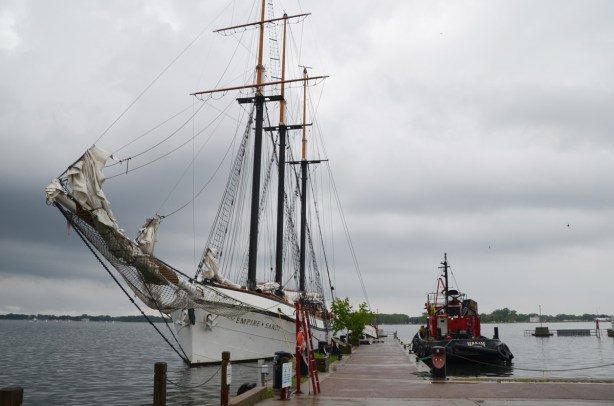 the Empire Sandy, a three mast sailing ship, docked along side a small tugboat, the M. S. Kane. on a grey wet day 