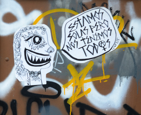 black and white paste up on a wall, Spansih words that say estamos solas pero nos tenemos todos