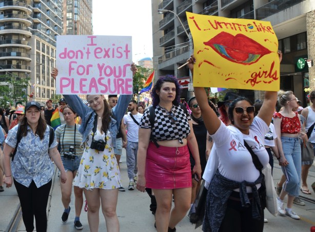 dyke march 2019, two women holding signs while marching in parade with other women