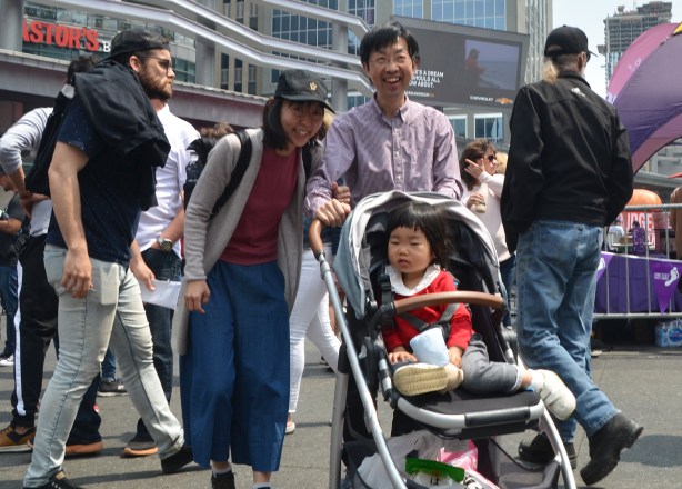 family group - mother and father laughing, baby in stroller, Asian, at Yonge dundas square