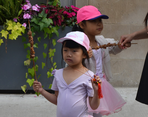 two little girls in pink with pink hats holding onto shish kebobs 