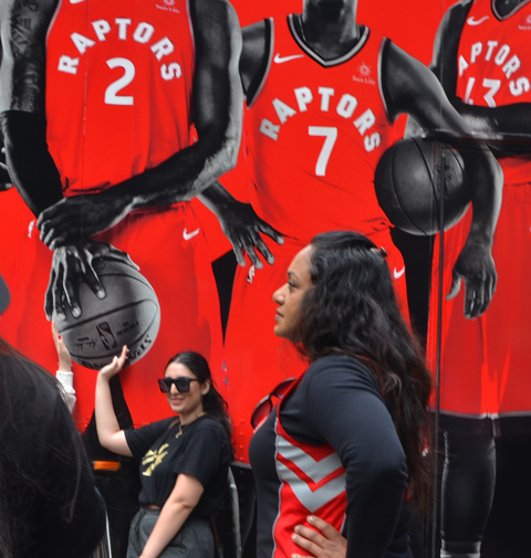 Raptors fans celebrating team's NBA championship, parade day in Toronto, a woman poses in front of a truck decorated with Raptors players pictures. 