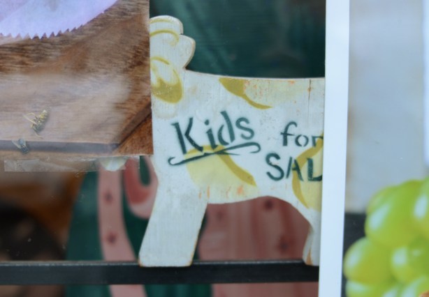 sign in a store window that says kids for sale 