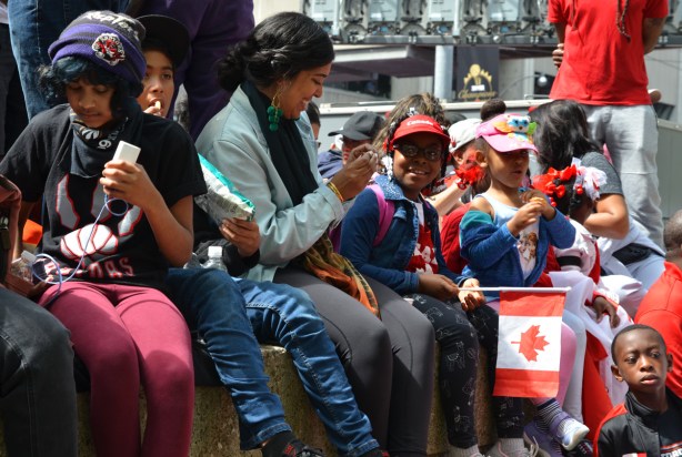Raptors fans celebrating team's NBA championship, parade day in Toronto, people sitting on a concrete barrier 