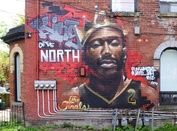 a mural on a red brick wall, King of the North, face of a basketball player, Toronto Raptors number 2, with a crown on his head, Kawhi Leonard