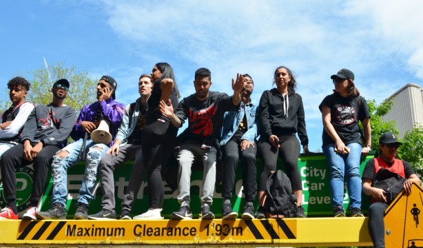 raptors fans sitting on top of a parking garage entrance, by their feet is a yellow sign that says maximum clearance 