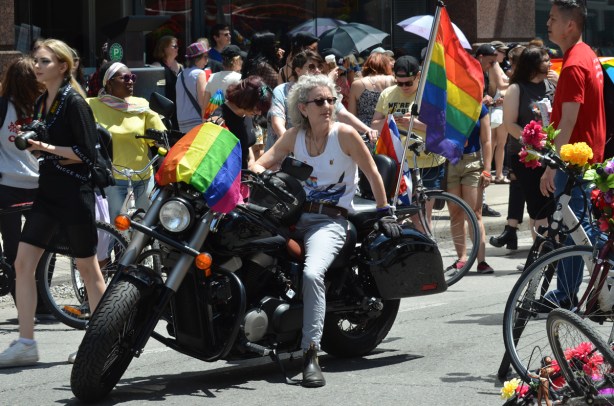 a woman sits on a motorcycle waiting for the dyke march to begin