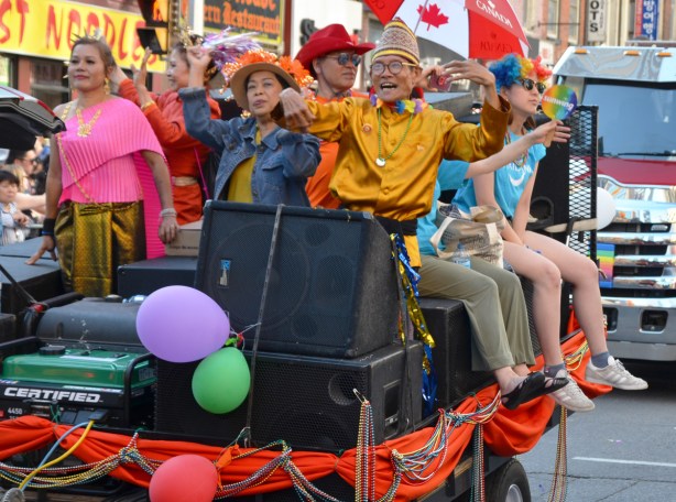 people on a float in a parade, one has a Canada umbrella 