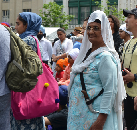 At Turbanup event at Yonge Dundas Square, an older woman with a white cloth over head head and a kirpan sword at her side