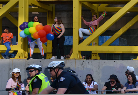 people using a large metal scaffolding structure on a construction project beside Yonge street to sit on to watch pride parade 