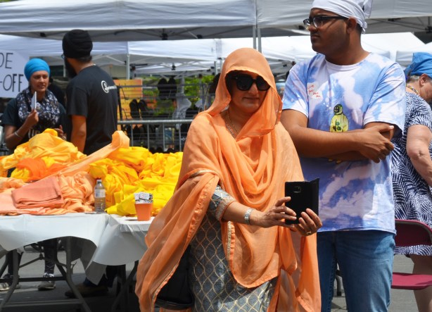 a woman with a light orange cloth draped over her head and around her shoulders and body takes a selfie