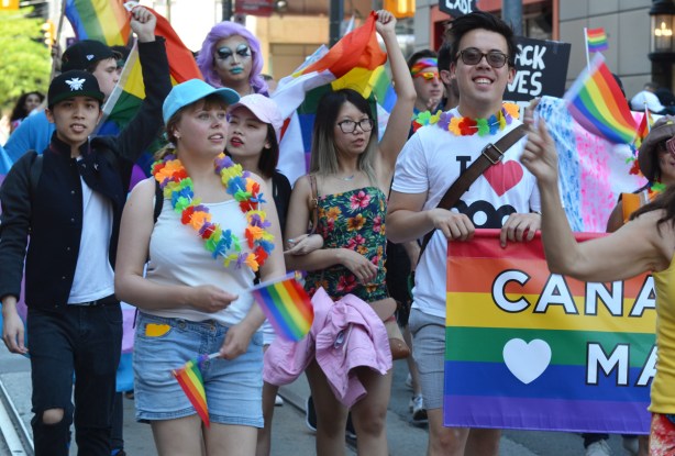 a group of people walking in the pride parade with rainbow flags and accessories