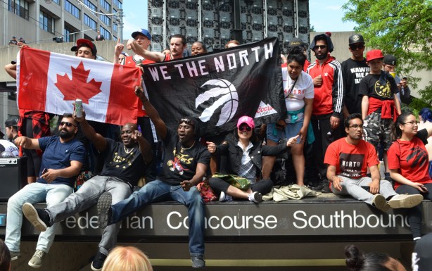 raptors fans with we the north banner and canadian flag sitting on top of entrance to parking lot