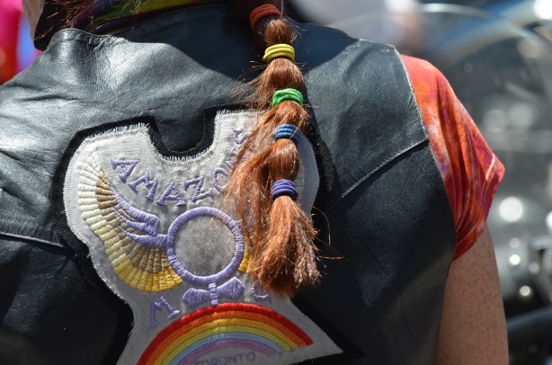 long red hair held in a ponytail by elastics of rainbow colours, on back beside badge on Amazon motorcycle club jacket