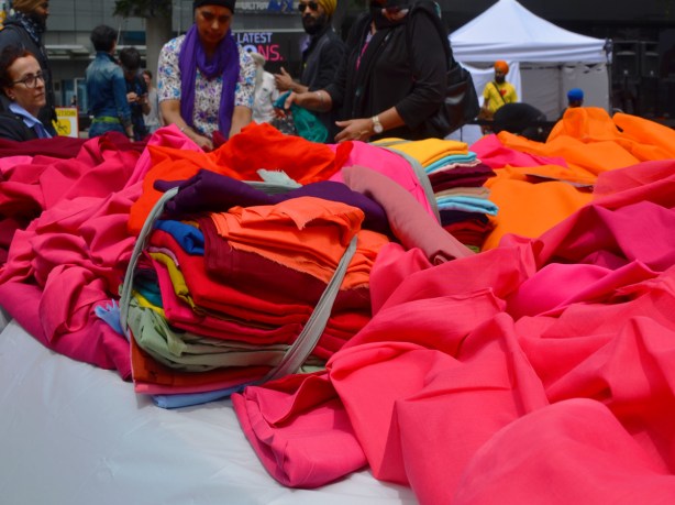 piles of colourful fabric on a table At Turbanup event at Yonge Dundas Square,