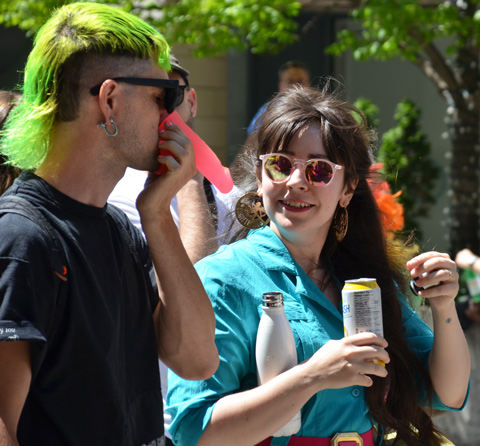 a person in short green hair holds a pink plastic dildo to his nose