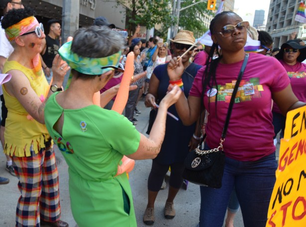 a woman reacts to seeing two older woman with small inflatable dolls