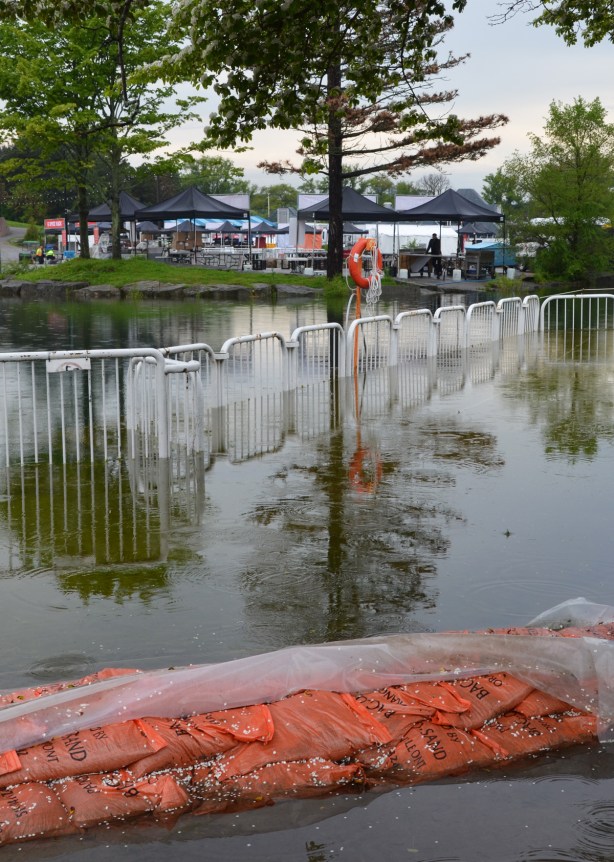 flooding at Ontario place, orange sandbags and a fence that is partially submerged in the water 