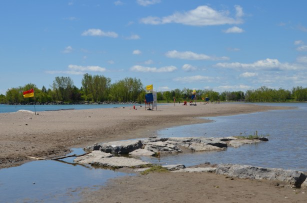 rocks and sand at Woodbine Beach, with water behind the lifeguard stations because of flooding of Lake Ontario 