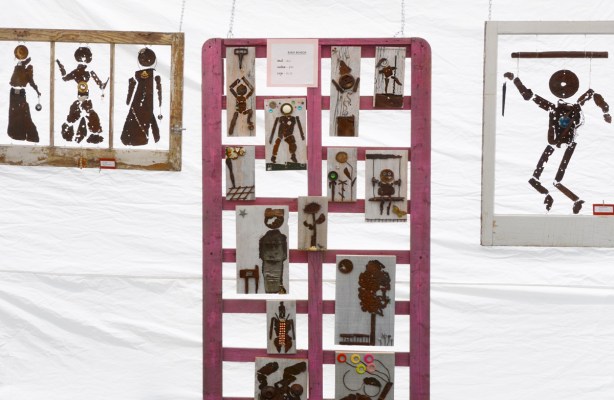 small artwork hanging on a white tent wall, light is coming from behind so they are silhouetted