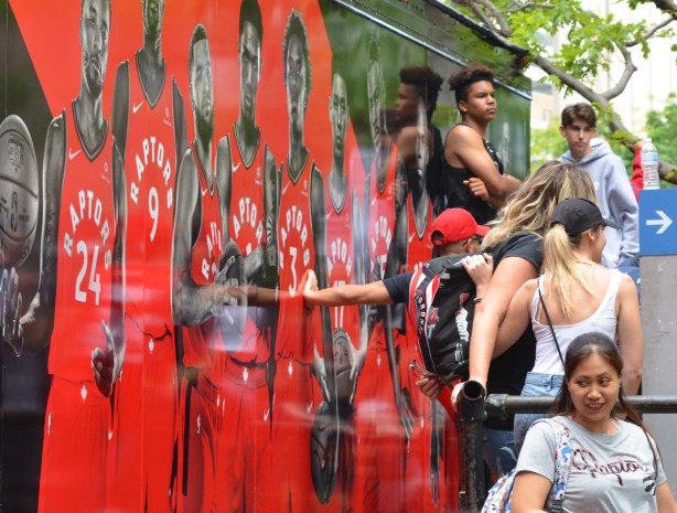 Raptors fans, parade day, leaning against the side of truck decorated with larger than life size pictures of Raptors players