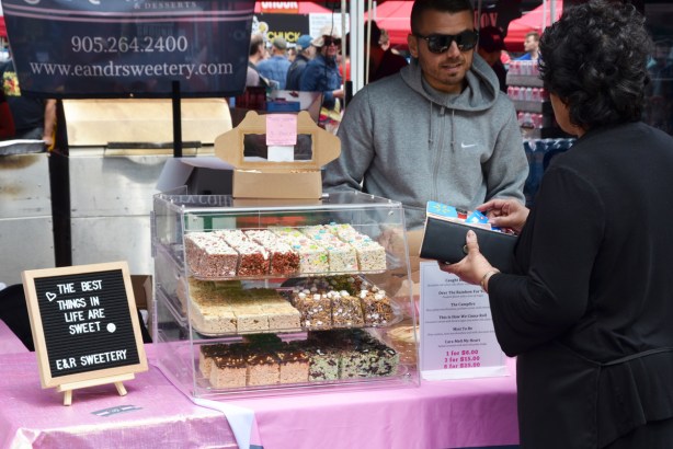 a man selling rice krispie squares and other desserts, outdoors, Yonge Dundas Square, from E and R Sweetery