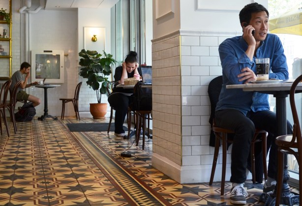 thre people sitting at different tables in a coffee shop