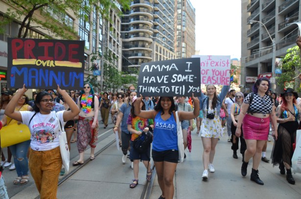 dyke march 2019, three women holding three signs while marching in parade