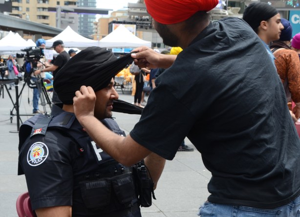 a policeman getting a black turban at Turbanup event at Yonge Dundas Square,