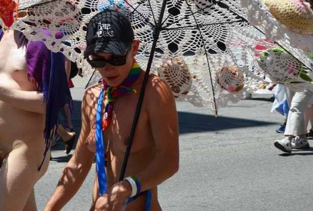 a nude woman carries a large white crocheted umbrella