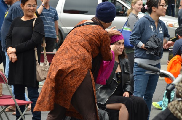 a woman watches another woman getting a turban