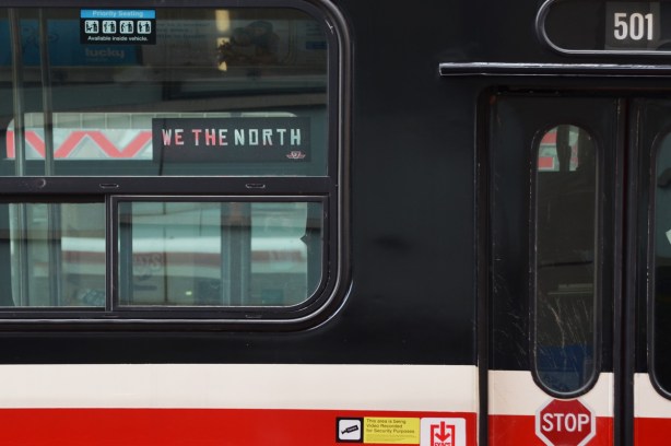 in the window of a TTC streeecar is a we the north sign 